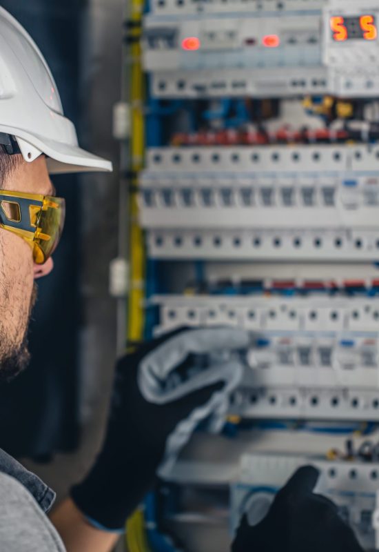 Man, an electrical technician working in a switchboard with fuses. Installation and connection of electrical equipment.